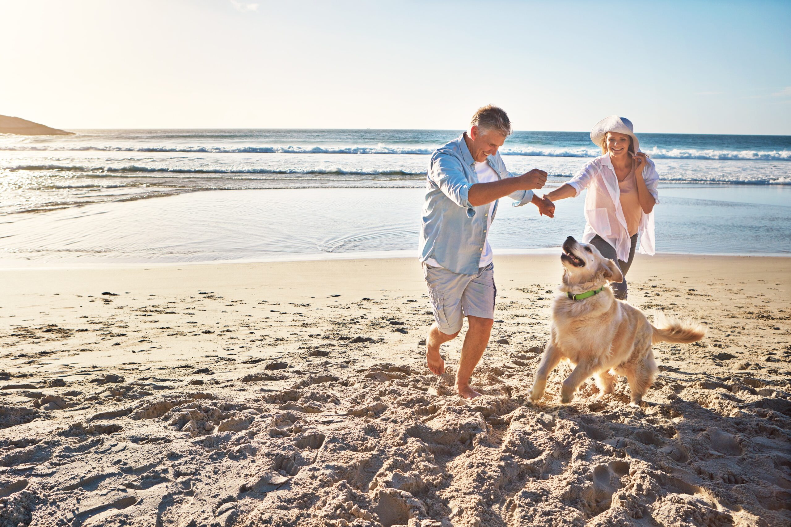 http://Man%20and%20woman%20on%20a%20beach%20with%20their%20dog